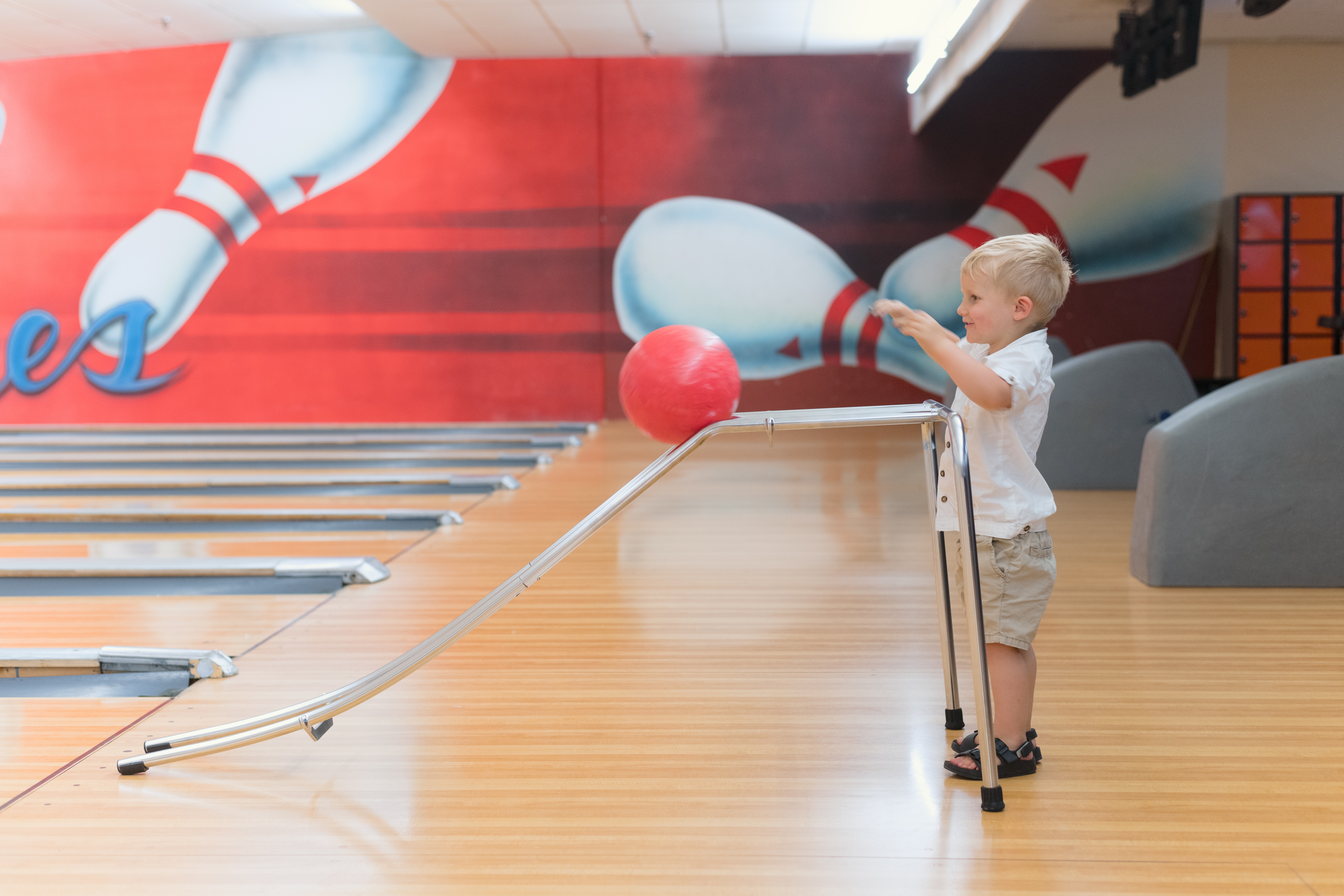 a young boy standing in a bowling alley.
