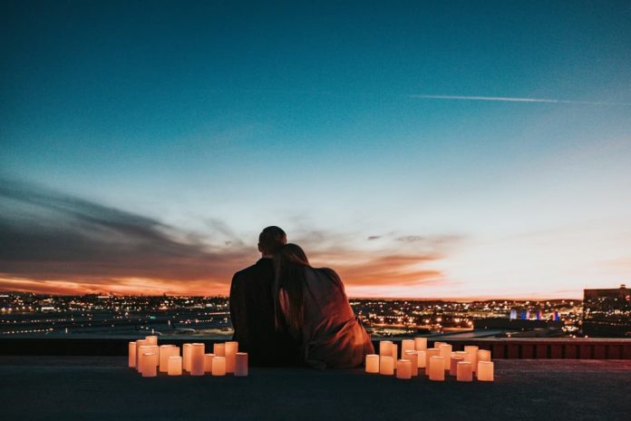 Image of a young couple looking over a valley city with romantic candles around