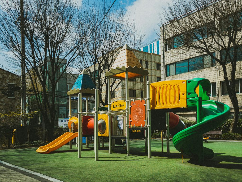 Children playing together on a playground while an adult supervises nearby